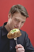 Man holding baked potato on fork