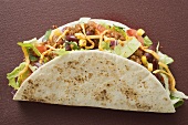 Taco filled with mince & cheese on brown background