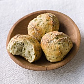 Three herb bread rolls with sesame seeds in wooden bowl