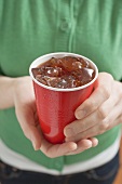 Woman holding cola in plastic cup