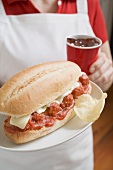 Woman holding meatball sandwich and cup of cola