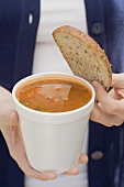 Woman holding tomato soup and slice of bread