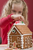 Small girl decorating gingerbread house