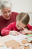 Kleines Mädchen mit Grossmutter schreibt Weihnachtsbrief