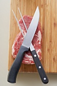 Beef steak on chopping board with meat knife and fork