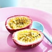 Passion fruit, halved, on plate with spoon