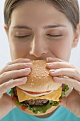 Young woman biting into cheeseburger