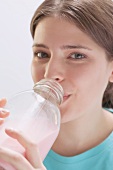 Young woman drinking strawberry milk out of bottle