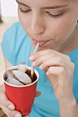 Young woman drinking cola through a straw
