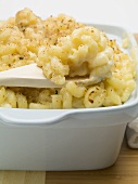 Macaroni cheese in baking dish with wooden spoon