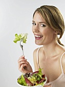 Woman eating mixed salad leaves