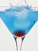 Blue Curaçao cocktail with cocktail cherry and ice cube