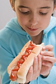Little girl eating hot dog with ketchup