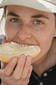 Woman biting into a buttered bread roll