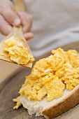 Child spreading scrambled egg on bread