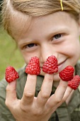 Mädchen mit Himbeeren auf den Fingern