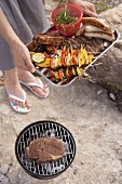 Woman serving grilled food in aluminium dish at barbecue by river