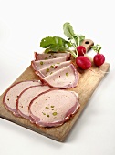 Several slices of breast of veal & radishes on chopping board