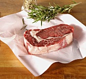 Raw rump steak on paper, rosemary, peppercorns
