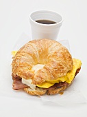 Croissant with bacon, scrambled egg & cheese, cup of coffee