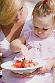 Mother and young daughter with a dish of strawberries