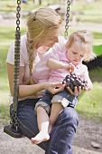Mother and young daughter eating grapes on a swing