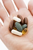 Assorted tablets and capsules on someone's hand