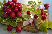 Radishes, whole and sliced, on chopping board