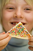 Boy holding fairy bread (Bread triangle with sprinkles, Australia)