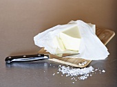 Butter in opened packaging on a wooden board with salt