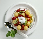 Melon, strawberry and kiwi fruit salad with yoghurt sauce and mint