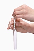 Hands holding litmus paper in test-tube