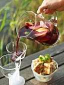 Man pouring sangria into glasses on a landing stage