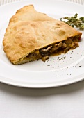 A piece of calzone with mushroom filling