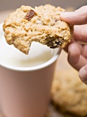 Hand holding cookie over a beaker of milk