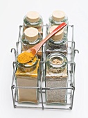 Various spices in small glass bottles and on spoon