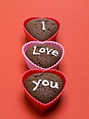 Heart-shaped chocolate muffins with white sugar writing