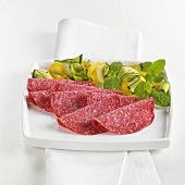 Slices of salami on plate with vegetable garnish