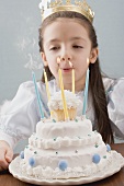 Kleine Prinzessin bläst Kerzen auf Geburtstagstorte aus