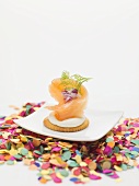 Smoked salmon on cracker on plate surrounded by confetti