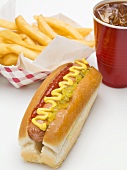 A hot dog, a portion of chips and a plastic cup of cola