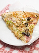 A slice of pizza topped with ham, olives and peppers
