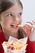 Mädchen ein Pommes Frites-Tüte haltend beim Essen