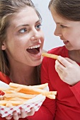 Young woman and girl eating chips together