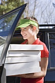 Smiling woman with several pizza boxes