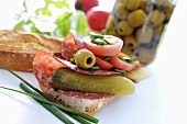 Salami, gherkin, olives and tomato on baguette