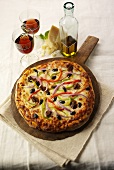Pizza mit Würstchen und Gemüse auf einem Holzbrett