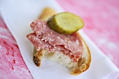 Salami and bread with gherkin, a bite taken