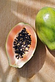 Half a papaya beside a whole papaya (overhead view)