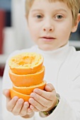 Little boy holding squeezed oranges